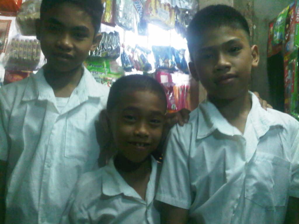Three boys in white school uniforms standing together in the Philippines
